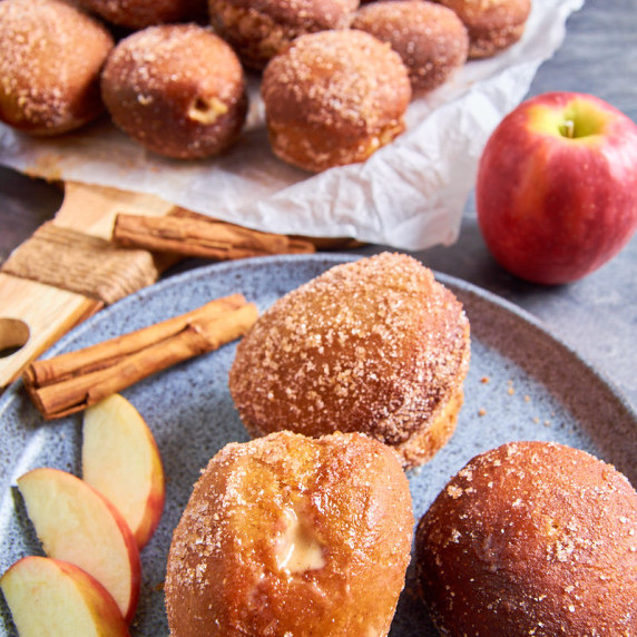 A plate with several Sourdough Apple Cider Donuts with Spiced Plum Curd rolled in cinnamon sugar