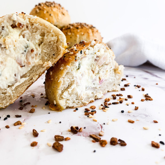 cross section of bagel bomb, showing red onion, capers, dill and smoked salmon cream cheese filling