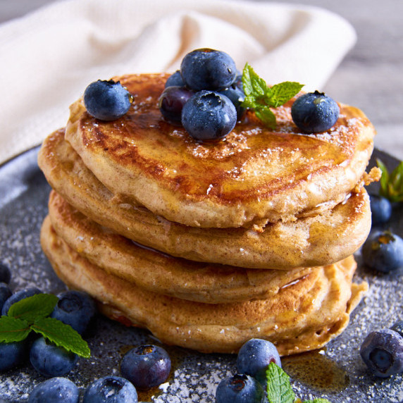 A stack of fluffy Sourdough Protein Pancakes with wholewheat, topped with blueberries