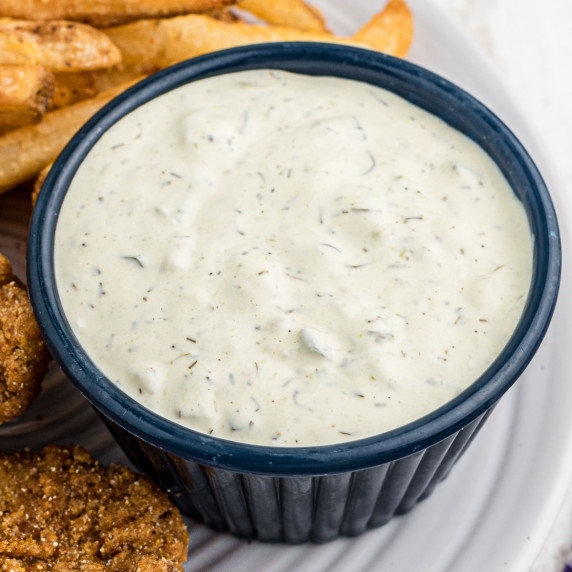 large dish of tartar sauce with some fried fish and french fries on the side.