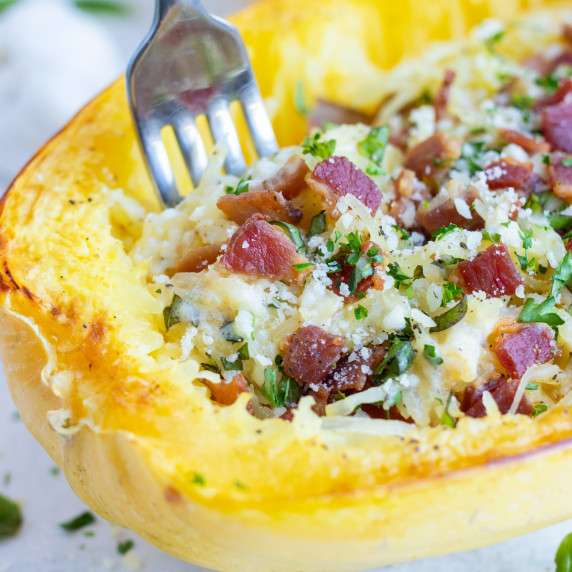 Spaghetti Squash Carbonara RECIPE garnished with bacon and served with a fork.