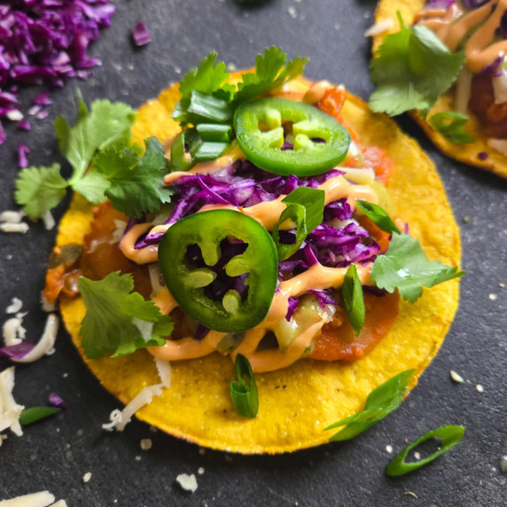 Golden tostada topped with a colourful assortment of ingredients & garnishes