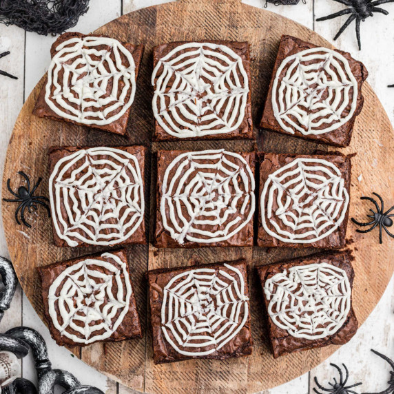 A board full of brownies decorated with spider webs.