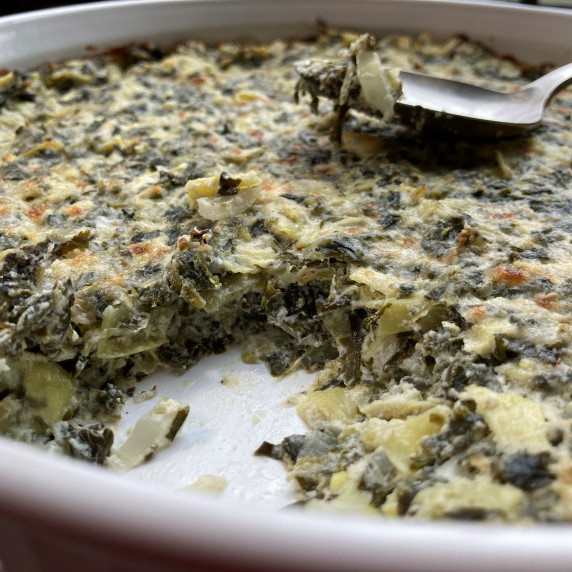 Spinach and artichoke dip in a white baking dish.