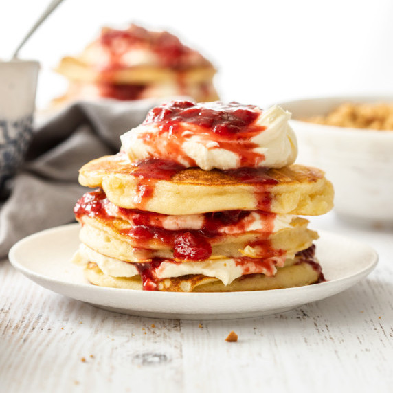 A stack of strawberry cheesecake pancakes on a white plate.