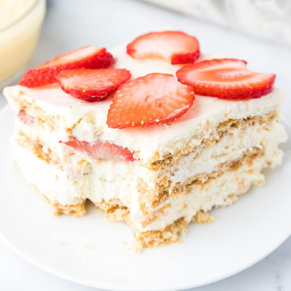 Up close view of a slice of strawberry cream cheese icebox cake on a plate missing a bite.