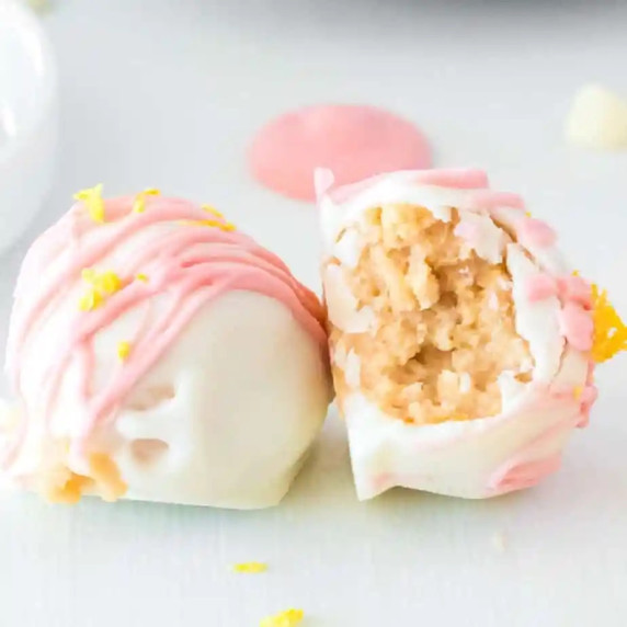 Two strawberry lemonade truffles side by side, one on it's side with a bite missing.