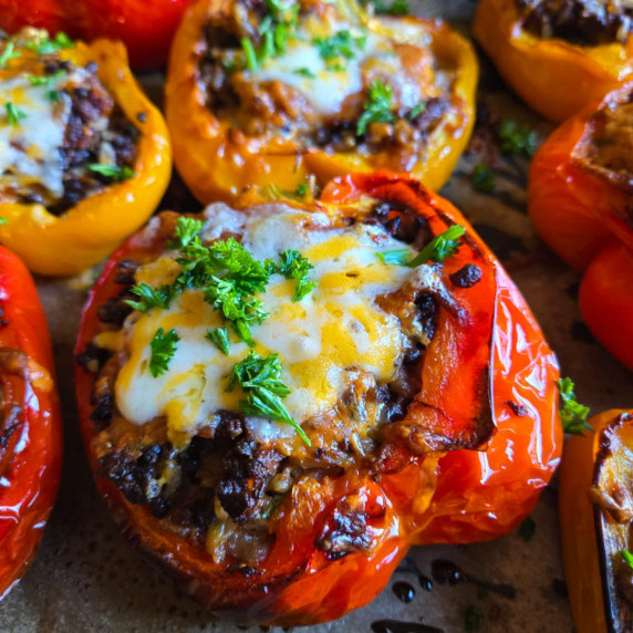 Red and orange peppers stuffed and topped with melty cheese and pops of green parsley.