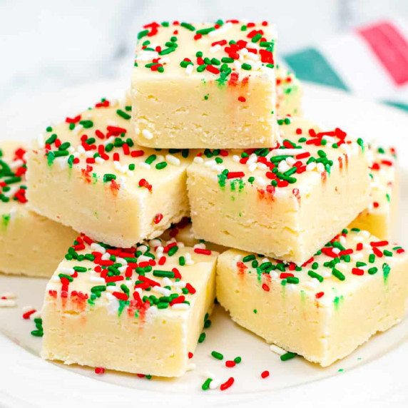 Tall stack of sugar cookie fudge covered in red and green sprinkles from the side.