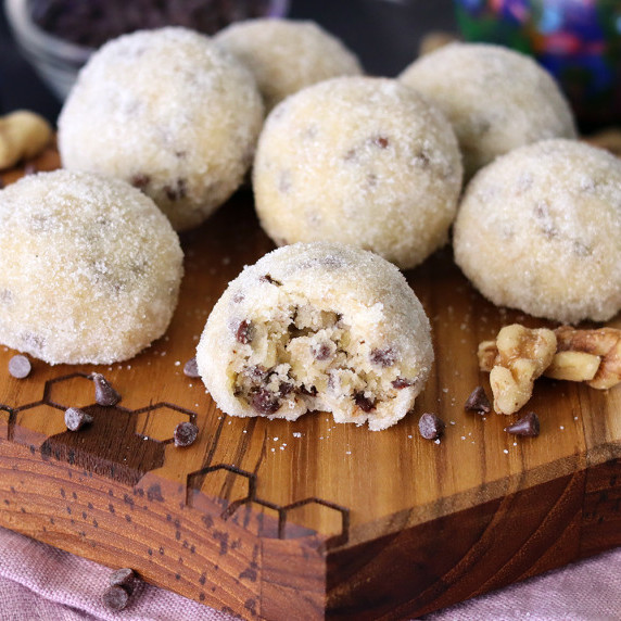Sugar coated melt-aways on a wooden board with a bite taken out of the foremost one