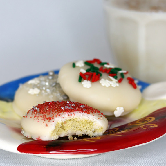 Sugar cookies on a holiday plate with a glass of eggnog against a white background