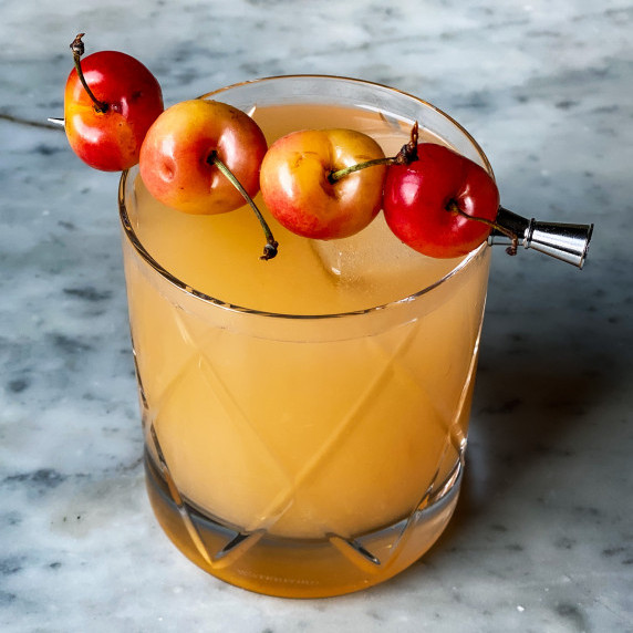 Waterford crystal glass with grapefruit and orange juice drink with cherries on top.