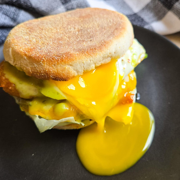 Golden yolk cascading down a toasty breakfast sandwich.