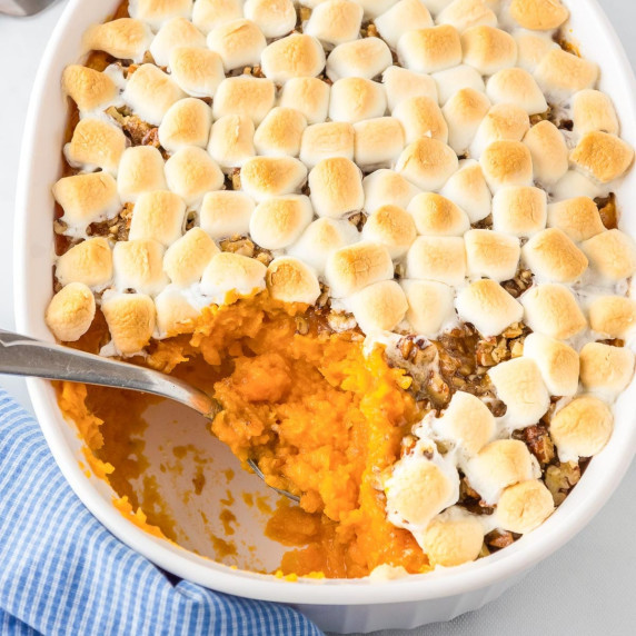 A casserole dish with sweet potato casserole topped with pecans and toasted marshmallows.