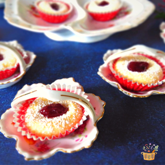 Swiss tarts with a dollop of jam in small dessert cups on a blue board
