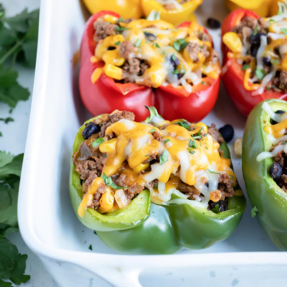 Mexican Stuffed Bell Peppers RECIPE served in a white platter topped with shredded cheese.