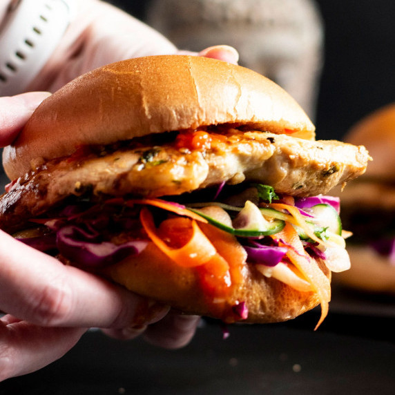 Two hands holding a Thai Chicken Burger with Tamarind Sweet Chilli Sauce