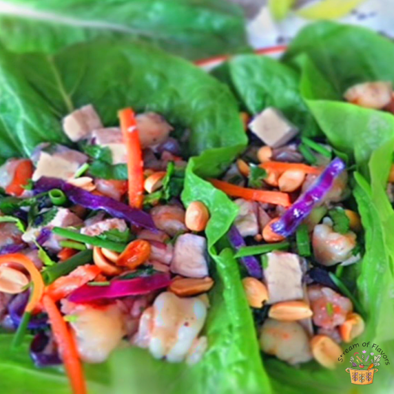 Thai Shrimp Lettuce Wraps with shrimp, tofu, carrots, peanuts, and cabbage in lettuce leaves