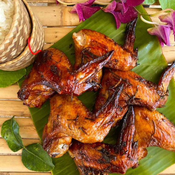 6 Pieces of Thai marinated chicken wings on top of a banana leaf.