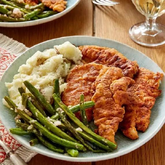 Mashed potatoes with hot chicken on a plate with green beans