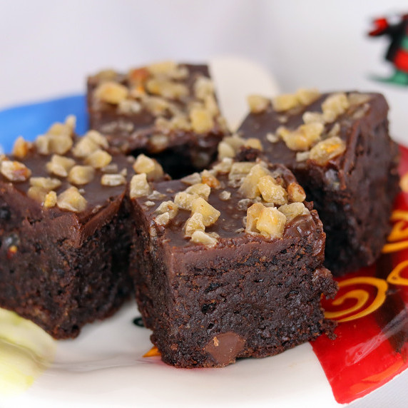 Toffee crunch flourless brownies on a holiday plate against a white background.