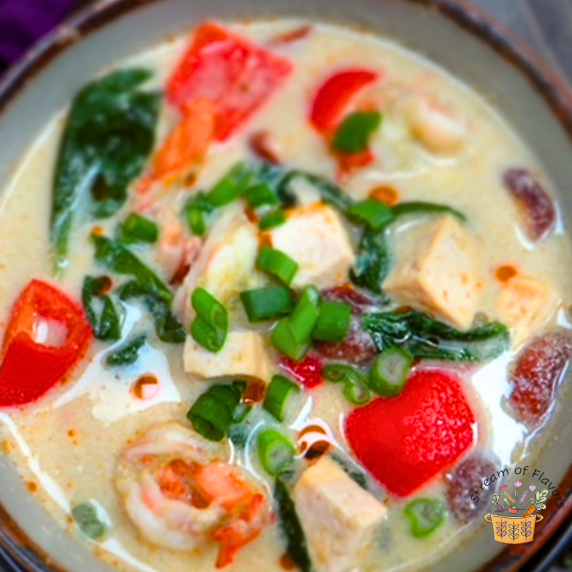 Tom Kha Goong with shrimp, bell peppers, tofu, and coconut milk in a bowl