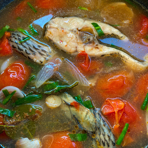 Close-up of tom yum pla, Thai fish soup, in a cooking pot.