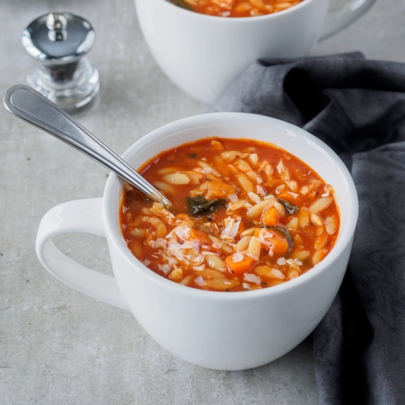 Large mug containing tomato orzo soup.