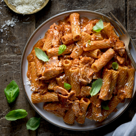 Rigatoni pasta with salmon in a creamy tomato sauce, sprinkled with parmesan and basil.