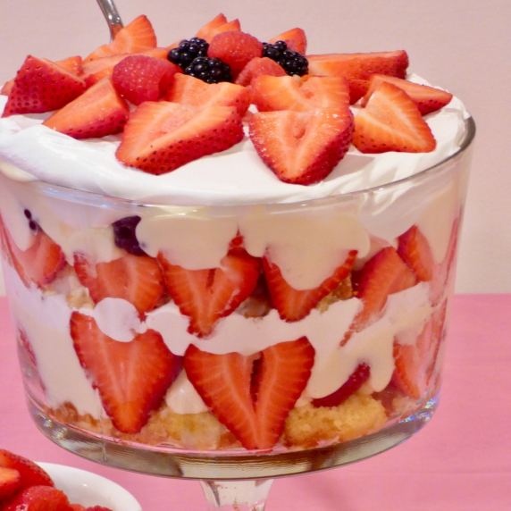 Triple berry trifle with cool whip on a table with a pink tablecloth.  