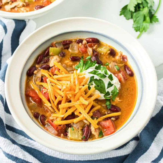 Turkey chili in a bowl topped with cheese, sour cream and parsley.