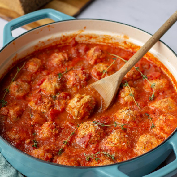 Turkey meatballs in a blue pan with a wooden spoon