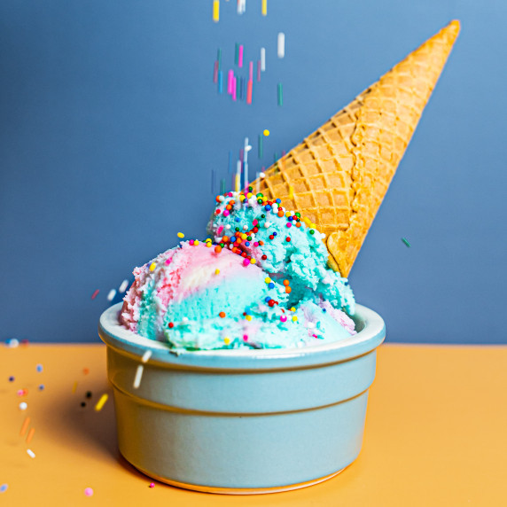 Upside-down pink and blue cotton candy ice cream with sugar cone and sprinkles