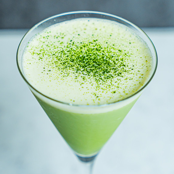 Matcha martini in a martini glass with matcha powder.