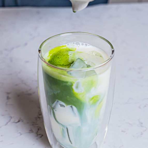 Iced matcha latte with green swirl in talk glass cup