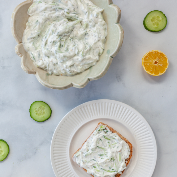 Tzatziki on toast and in bowl with cucumber on table 