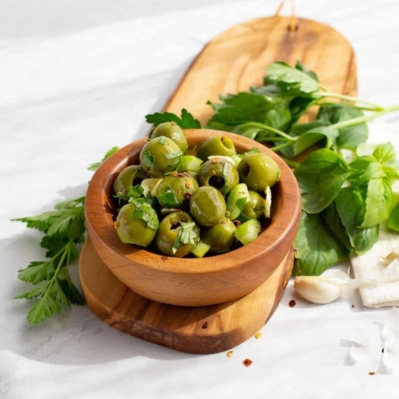 Marinated Sicilian olives with a sprinkle of fresh parsey and chili pepper flakes on top in a bowl