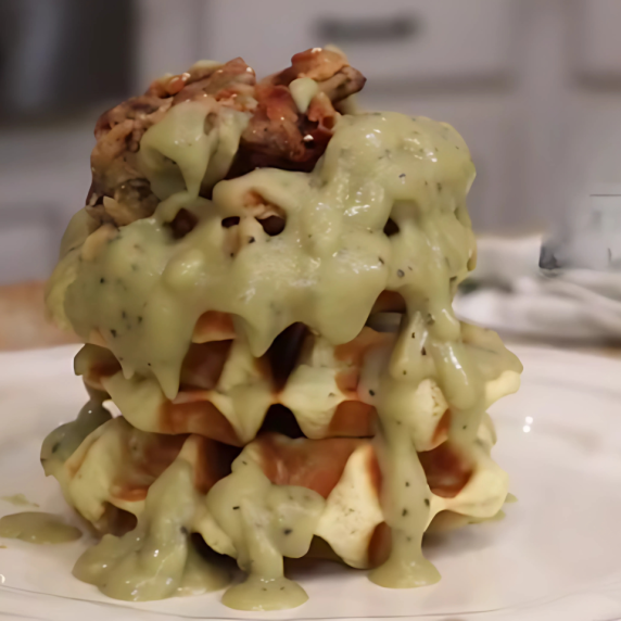  A stack of fluffy vegan waffles topped with crispy chick’n fried jerky and smothered in creamy navy
