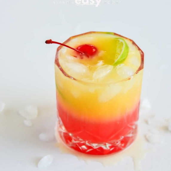 Glass of malibu sunrise drink with ice, cherry, and lime slice on top 