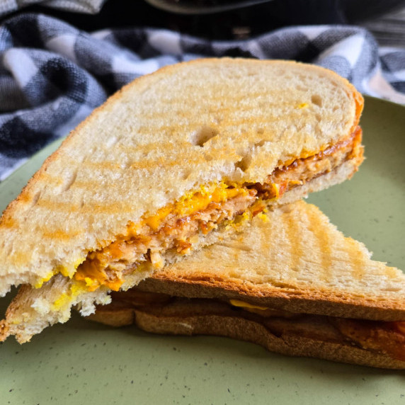 Lightly grilled sandwich with a checkered towel in the background.