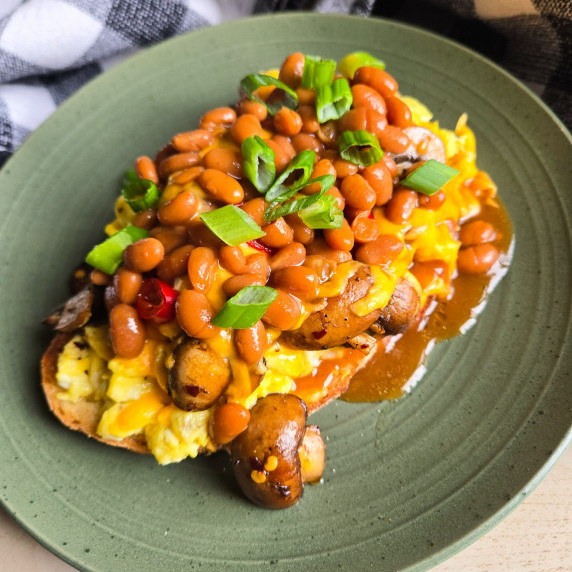 Golden toastie topped with egg scramble, saucy baked beans & green onions