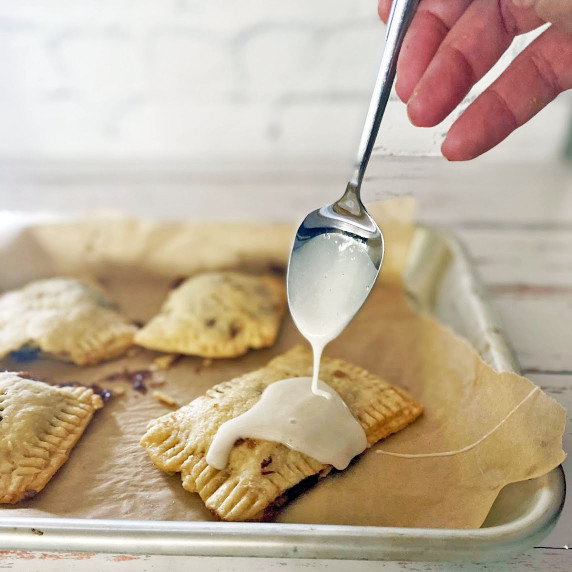 Spoon with icing going on the pastry