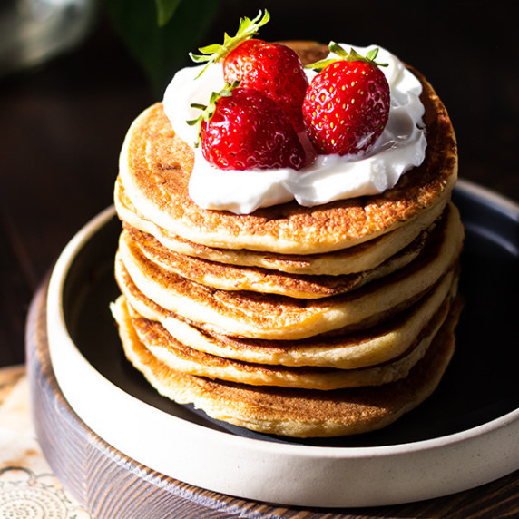 stack of Vegan Buttermilk Pancakes served with coconut yogurt and fresh strawberries