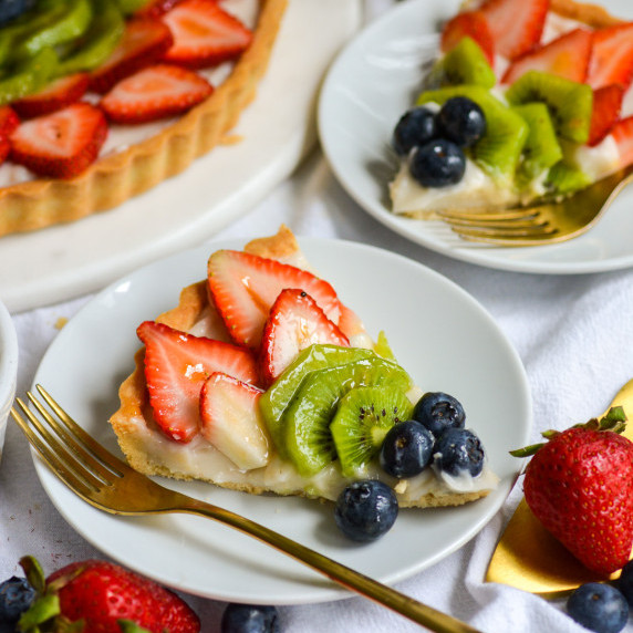 A vegan fruit tart topped with sliced strawberries, kiwi and blueberries.