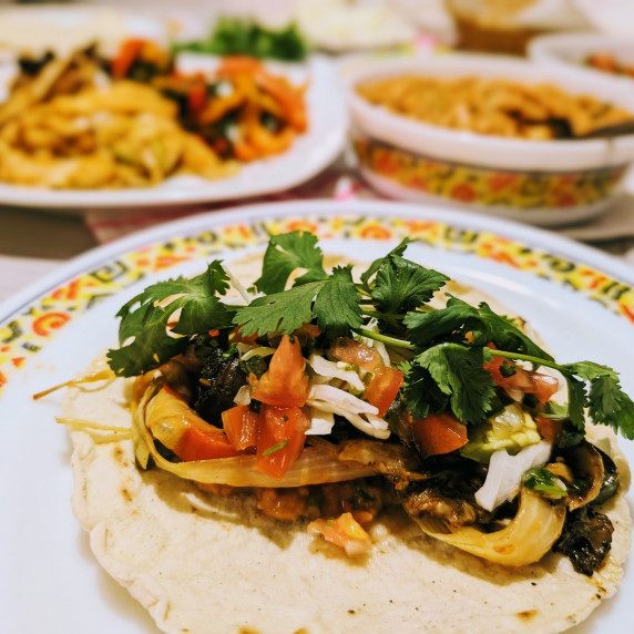 a vegan mushroom and pepper fajita with all the fixings on a plate