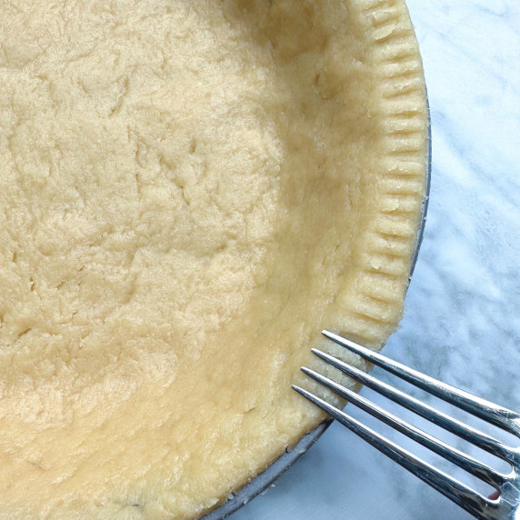 uncooked vegan pie crust with fork making impressions