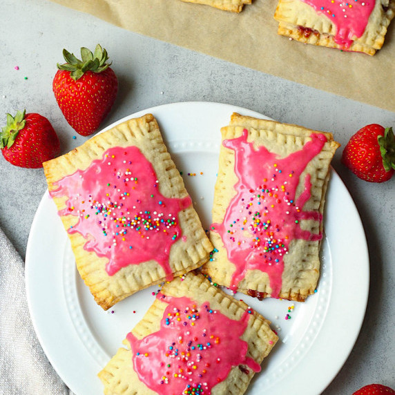 vegan pop tarts with pink frosting and rainbow sprinkles arranged on a white plate
