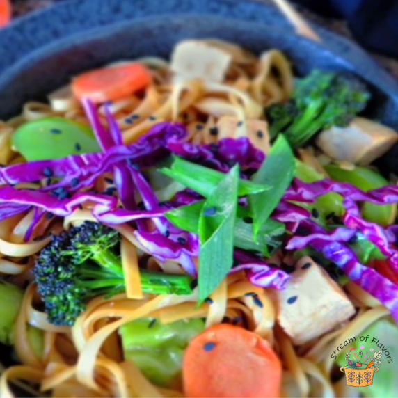 Vegetable Chow Mein with noodles, broccoli, cabbage, spring onions, tofu in a black bowl