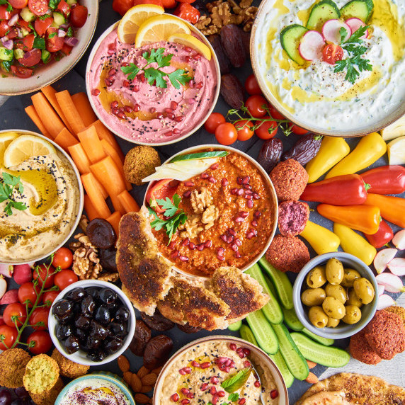 A Vegetarian Mezze Feast spread out on slates surrounded by vegetables, fruits and olives