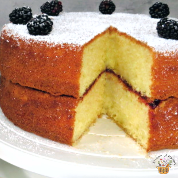Traditional Victoria Sandwich Cake with blackberry jam, dusted with sugar, topped with blackberries